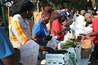 a group of people standing at a table with boxes of food